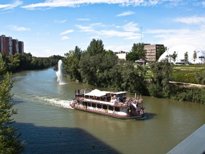 a boat floating along a river next to a body of water