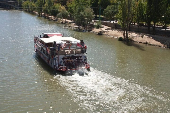 a boat traveling along a river next to a body of water